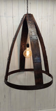 Load image into Gallery viewer, Whiskey Barrel Chandelier with oversized Edison Bulb  Constructed with four barrel staves, joined at the top by 4-way crossed barrel ring metal; secured at the bottom by full barrel ring 2-ring barrel ring accents evenly distanced between top and bottom on all four staves Chandelier has a three foot hanging chain Dimensions : 33in H, 25in diameter. Light is illuminated.
