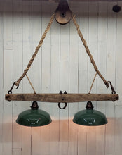 Load image into Gallery viewer, Suspended from a single wheel barn pulley by a vintage hemp rope, two barn shade with Edison lights attached to a horse yoke make up this rustic chandelier.  The barn shades display their original green paint, and timeworn patina.  Dimensions are 38 in W, 44 in H.  Lights are illuminated.
