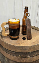 Load image into Gallery viewer, Whiskey Barrel Stave Bottle Opener on top of a whiskey barrel next to a poured mug of ale.  Opener is leaning against a empty beer bottle.
