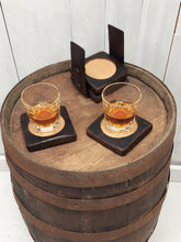 Load image into Gallery viewer, A top view of four coasters fashioned from whiskey barrel staves displaying two whiskey filled glasses on top of a rustic whiskey barrel.
